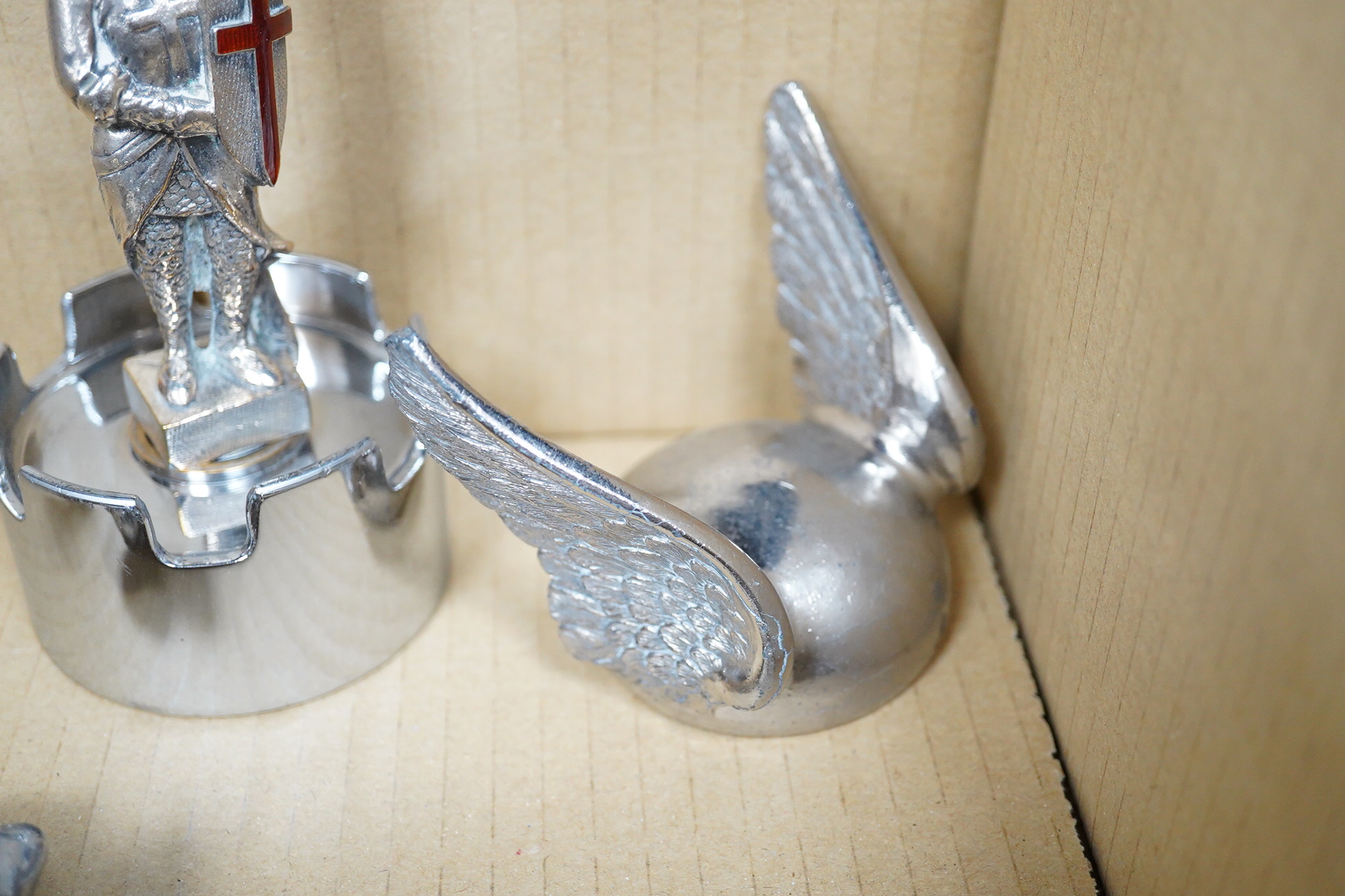 Seven chrome and brass car mascots, including two RAC logos, a head of Minerva, a crusader atop of a castellated pediment, a figure of Saint Christopher, a winged helmet, etc.